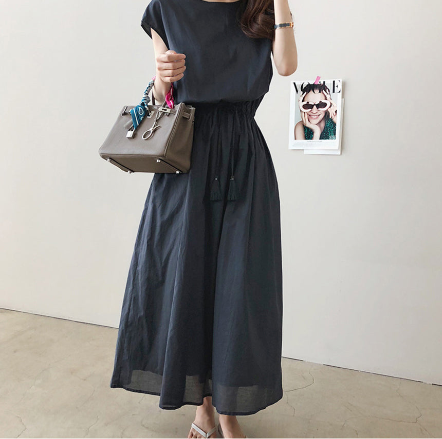 a woman in a black dress holding a brown bag