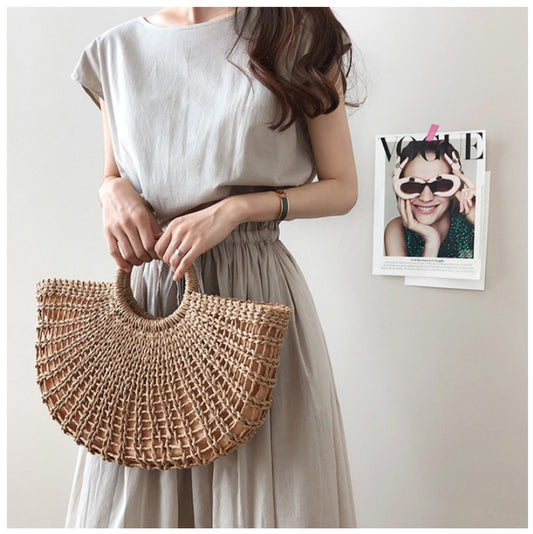 a woman holding a straw bag next to a wall